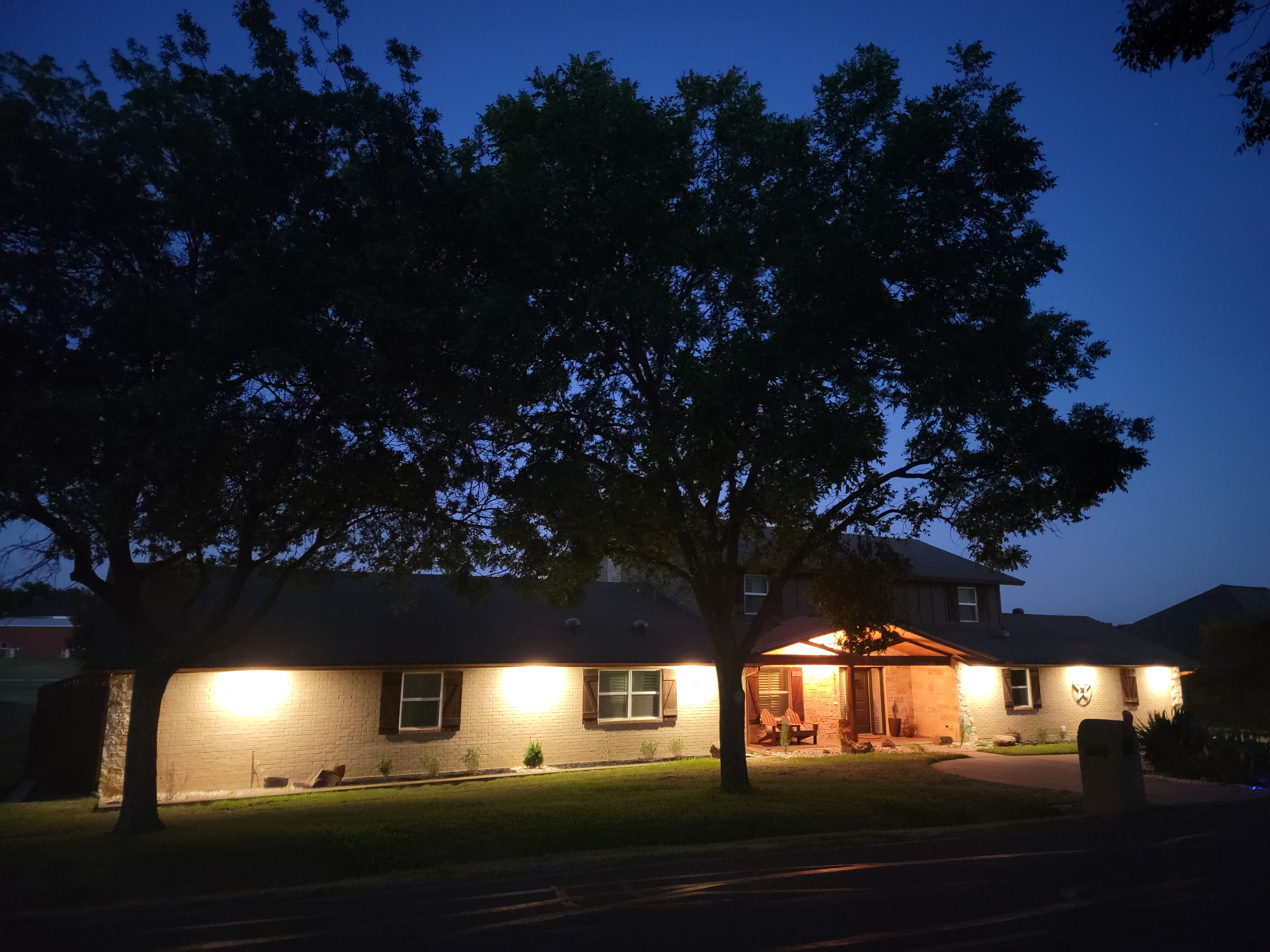 Front of house at night with warm copper porch glow and blue-hour sky