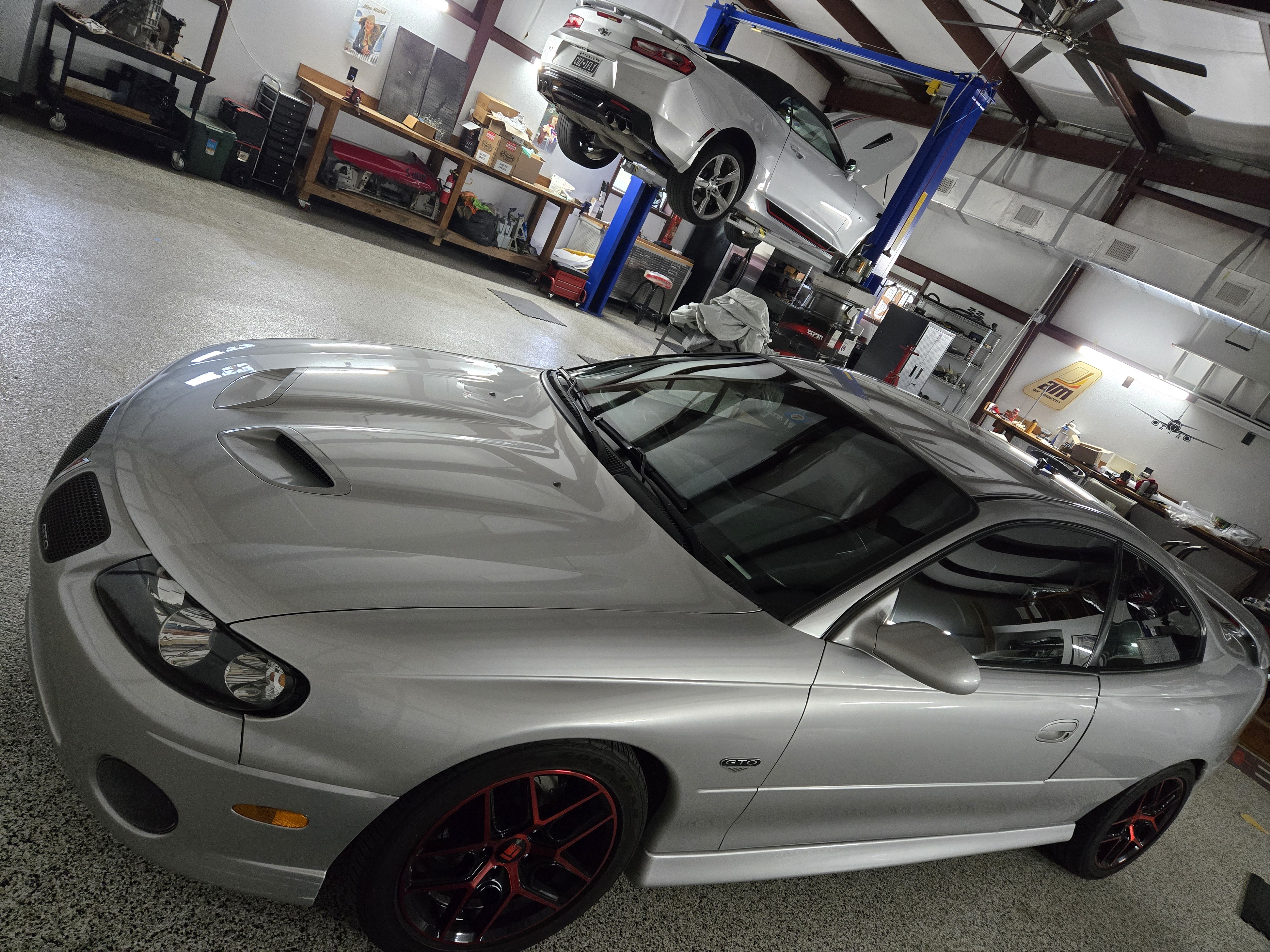 Automotive post lift in use with Camaro elevated, GTO in foreground