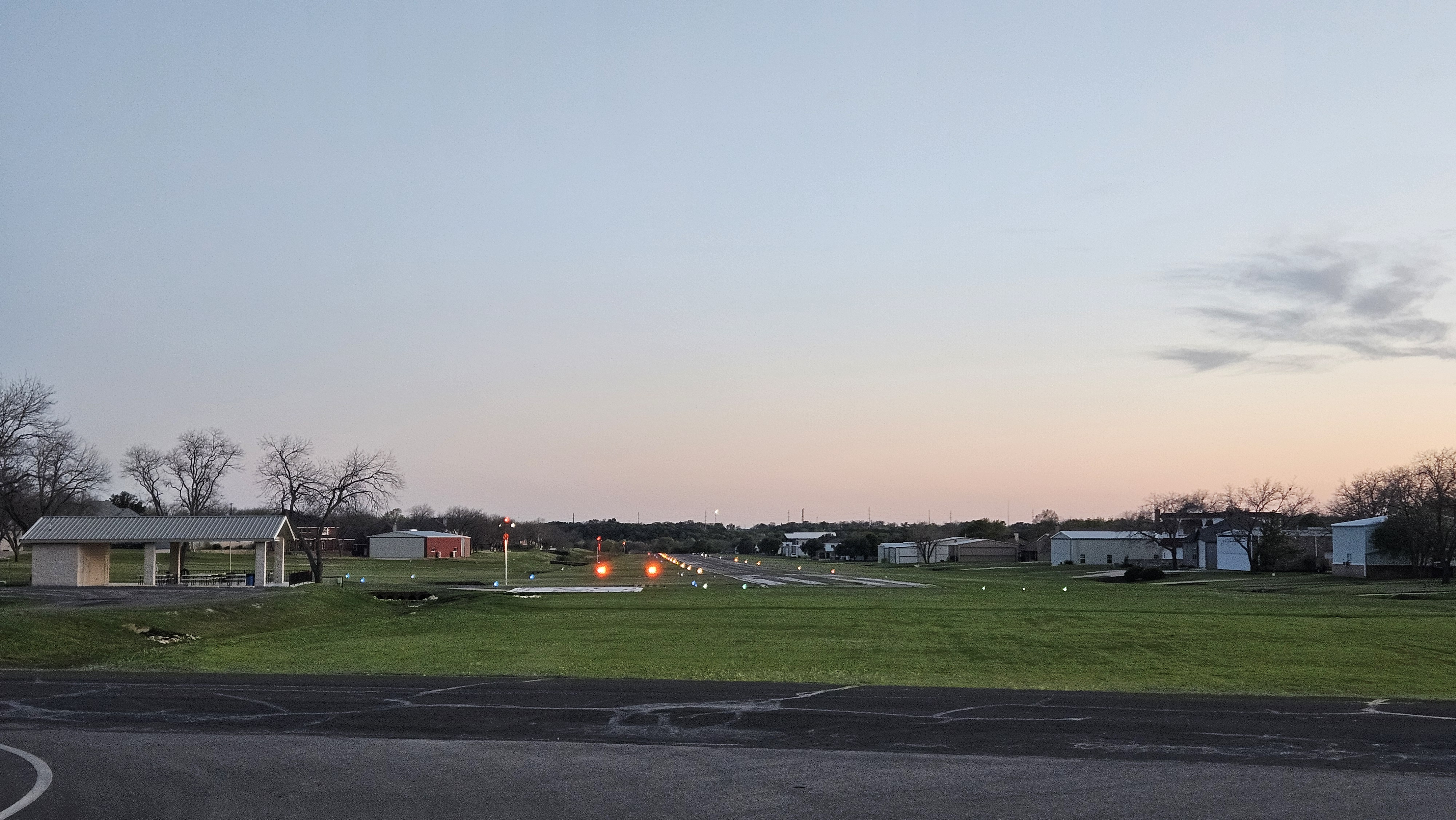 0TX1 runway at twilight with PAPI and edge lights glowing against pink-blue sky