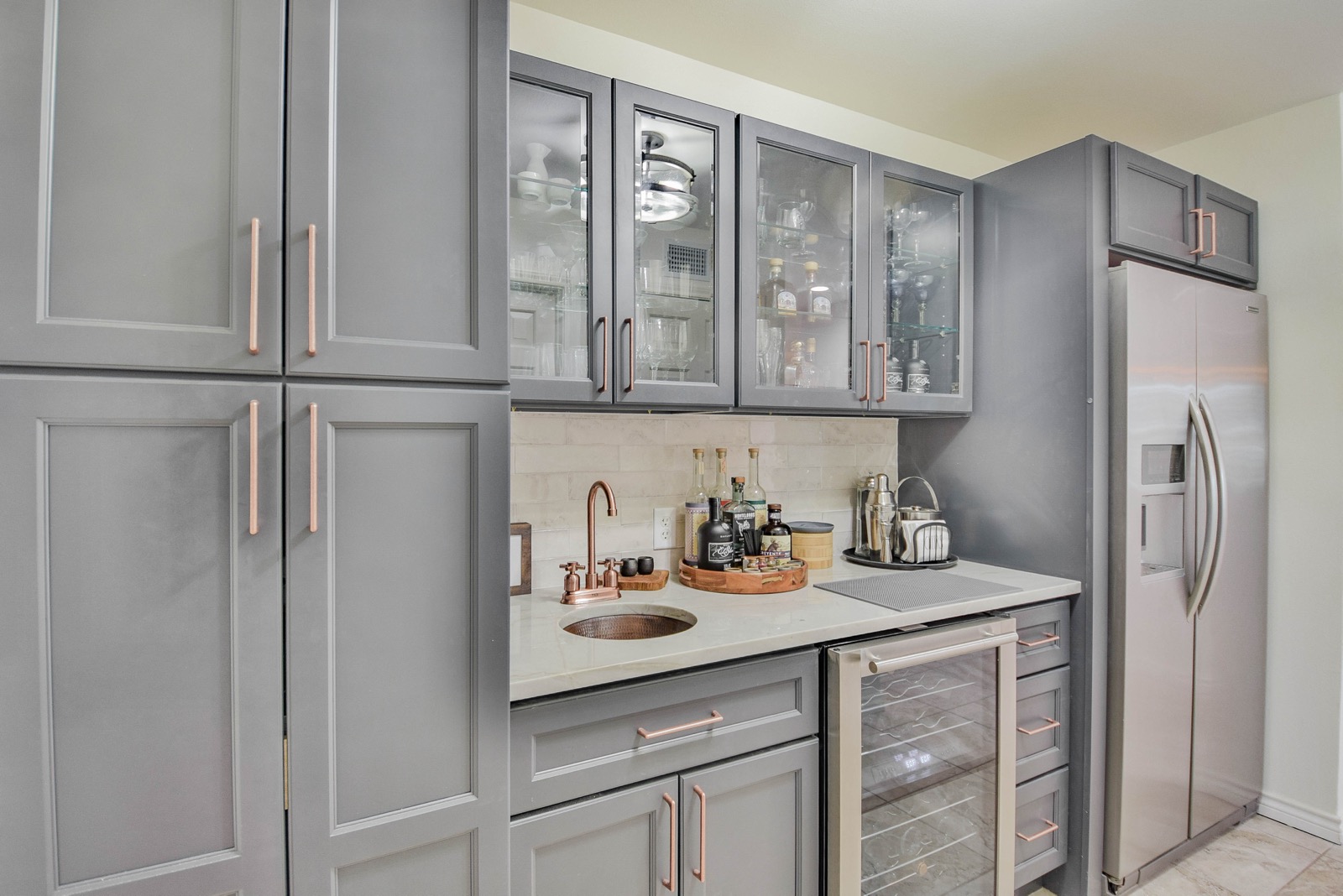 Wet bar with gray cabinets, copper hardware, copper round sink, wine cooler